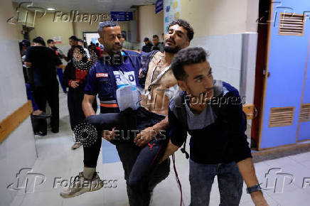 A paramedic carries a Palestinian man wounded in an Israeli strike, at Nasser Hospital, in Khan Younis