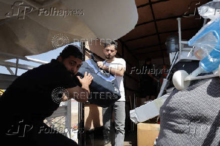 Syrian returnee Ahmed Al-hadid, and his family members load belongings onto a truck, in Aleppo's countryside