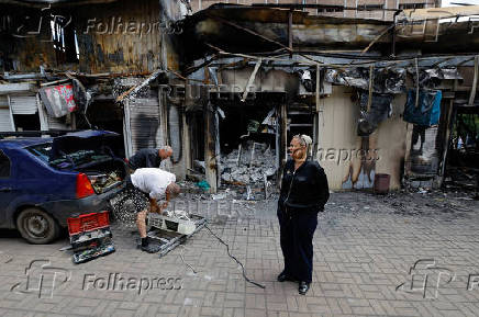 A shop owner shows the damage to her store following the shelling of a market in Donetsk