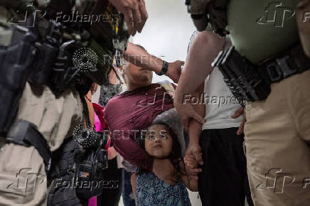 A child looks up at federal immigration officers as her father is detained at U.S. immigration court in Manhattan