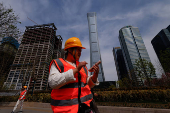 Construction workers walk past buildings at Central Business District (CBD) in Beijing