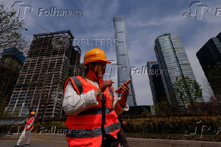 Construction workers walk past buildings at Central Business District (CBD) in Beijing
