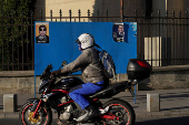A motorcycle passes by electoral posters of Nicusor Dan and George Simion in Bucharest