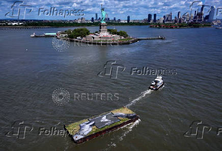 Drone view shows a grass covered barge with painting by Franco-Swiss artist Saype entitled ?Address Hate? towed past Statue of Liberty in New York Harbor