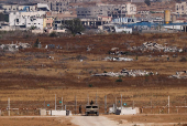An Israeli soldier walks next to a vehicle, as seen from Israel