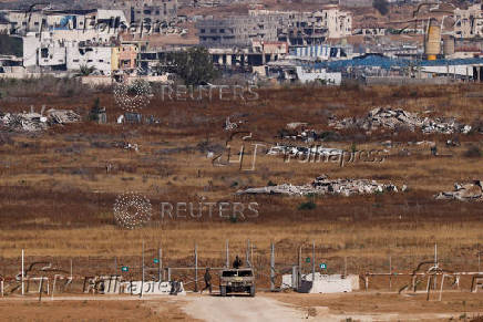 An Israeli soldier walks next to a vehicle, as seen from Israel