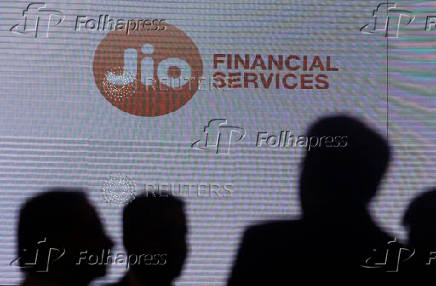 FILE PHOTO: People stand next to a logo of Jio Financial Services ahead of its listing ceremony at the Bombay Stock Exchange in Mumbai