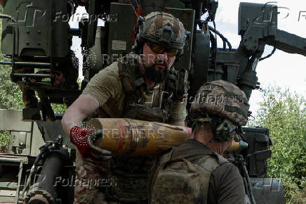 Ukrainian servicemen load a shell into a self-propelled howitzer before firing towards Russian troops near a front line in Kharkiv region