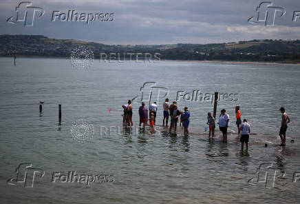 People use nets to try and catch crabs from a partially submerged jetty at Rhos-on-Sea, Wales