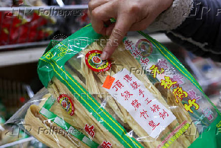 FILE PHOTO: Sun Vin Grocery Manager Jasmine Bai points at the packaging and price of dried bean curd imported from China at the store in Chinatown in New York