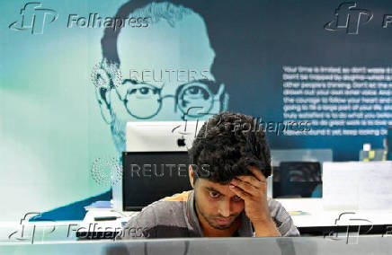 FILE PHOTO: An employee works on a computer terminal against the backdrop of a picture of late Apple co-founder Jobs at the Start-up Village in Kinfra High Tech Park in Kochi