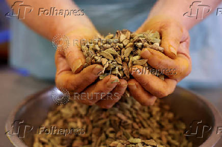 A staff member carries a handful of Cardamom pods at Spice Kitchen, as the company reacts to U.S President Donald Trump's tariffs, in Liverpool