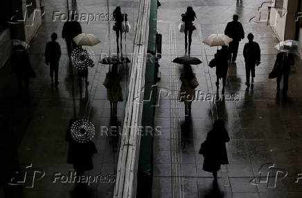 FILE PHOTO: Pedestrians are reflected on a wall of a shopping mall in Tokyo