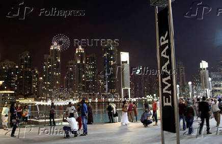 FILE PHOTO: People have their pictures taken near an Emaar sign outside the Dubai Mall