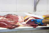 Açougueiro manipula peças de carnes em estabelecimento comercial especializado