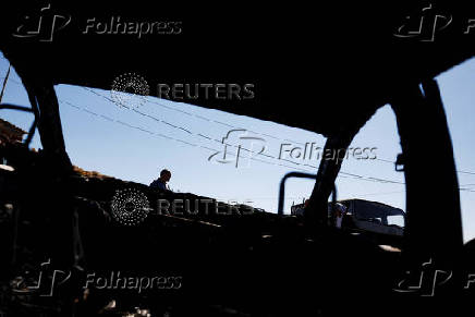 A Palestinian man inspects burnt cars, after Israeli settlers set fire to cars in the Palestinian town of Burqa