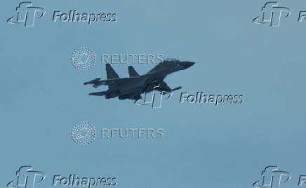 An aerial view of a Chinese fighter jet flying close to a Philippine Coast Guard aircraft carrying journalists, over the disputed Scarborough Shoal