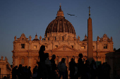 People walk in front of St. Peter's Basilica in St. Peter's Square ahead of the conclave, which will be held on May 7, at the Vatican
