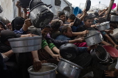 Displaced Palestinians collect donated food in Khan Yunis, southern Gaza