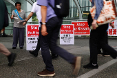 A protester releases leaflets against Nissan Motor's turnaround plan in front of the company's global headquarters while its annual shareholder meeting is being held in Yokohama