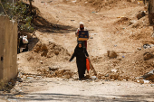 Palestinians carry their belongings after Israel's decision to demolish their homes in Nur Shams camp