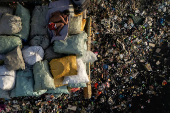 A drone view shows a boy sleeping on sacks of garbage along the polluted Pasig River on World Environment Day in Manila