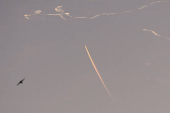 A military aircraft flies in the sky following a barrage of missiles launched from Iran, as seen over Tubas