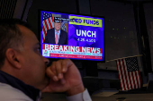 A screen displays the Fed rate announcement as traders work on the floor of the NYSE in New York