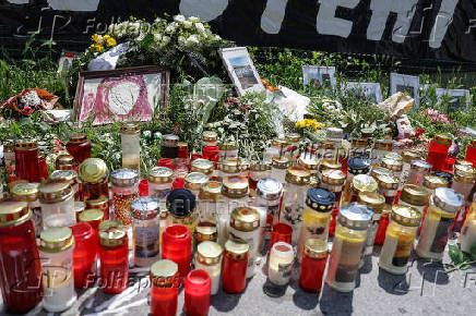 Flowers and candles are seen in front of the fences of the school in Graz