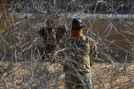 Members of the U.S. military replace concertina wire at on the U.S.-Mexico border, as seen from Ciudad Juarez