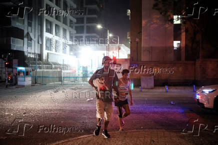 Israelis react at an impact site following a missile attack from Iran on Israel, at Tel Aviv