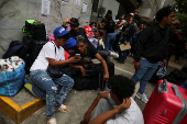 Migrants gather outside the Venezuelan embasssy waiting for a flight back to their country