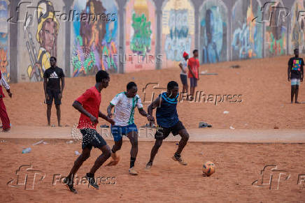 Men play soccer near a graffiti mural in Yoff, neighborhood of Dakar