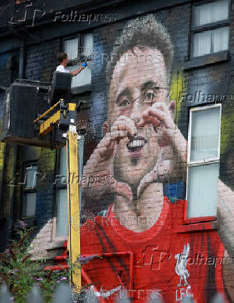 Artist John Culshaw works on a mural of late Liverpool player Diogo Jota on the side of a pub in Liverpool