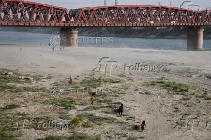 FILE PHOTO: People walk on the dry riverbed of the Indus River in Hyderabad, Pakistan