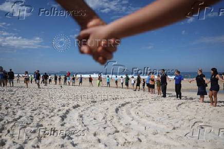 People attend a symbolic ritual named 'O Abraco' marking the World Oceans Day, at Sao Conrado beach in Rio de Janeiro