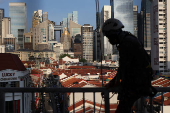 A worker climbs over a railing in the backdrop of the central business district skyline in Singapore