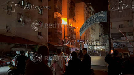 People gather near a building where a floor caught fire following an Israeli strike, in which the Israeli military said, it killed Hamas commander Hassan Farhat, in Sidon