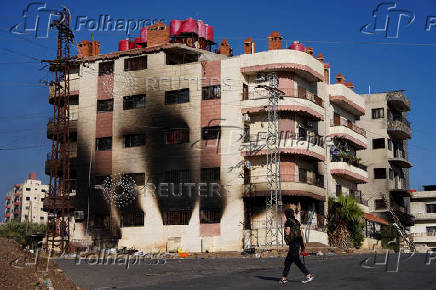 FILE PHOTO: A bedouin fighter walks near a burnt building, in Sweida