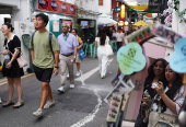 Youths take photos along a shopping street in Kampong Glam district in Singapore