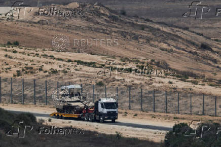 A truck carries a tank as it drives on the Israel side of the Israel-Gaza border