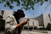 Woman walks past the headquarters of the People's Bank of China, in Beijing