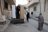 Syrian returnee Ahmed Al-hadid, and his family members unload belongings from a truck, in Aleppo's countryside