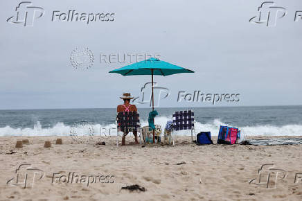 A woman sits under an umbrella at Flying Point Beach in Water Mill, New York