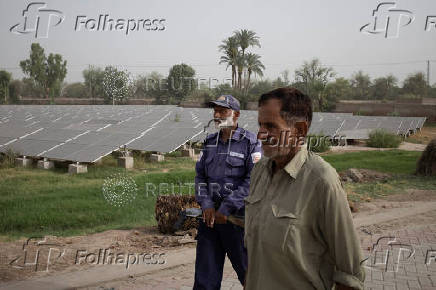 Men keep guard over a solar power facility in Multan