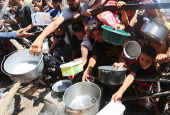 Palestinians gather to receive food from a charity kitchen, amid a hunger crisis, in Nuseirat