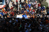 Mourners carry the body of a Palestinian journalist, Suleiman Hajjaj, who was killed in an Israeli airstrike, in Gaza City