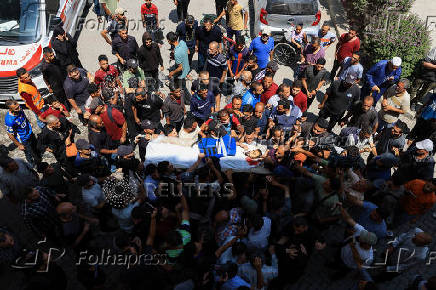 Mourners carry the body of a Palestinian journalist, Suleiman Hajjaj, who was killed in an Israeli airstrike, in Gaza City