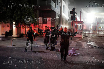Security personnel react at an impact site following a missile attack from Iran on Israel, at Tel Aviv