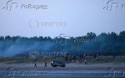 Police use tear gas to disperse a group of migrants trying to cross the beach to reach a dinghy whilst trying to cross the English Channel on a beach at Gravelines